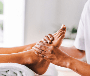 Therapist massaging a client's bare foot during a spa or foot massage session.